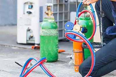 AC technician adding gas to an HVAC system